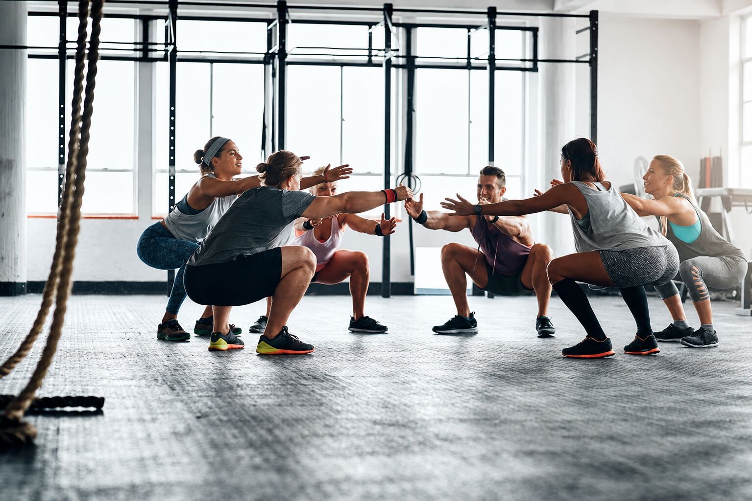A group class holding a squat together in a circle